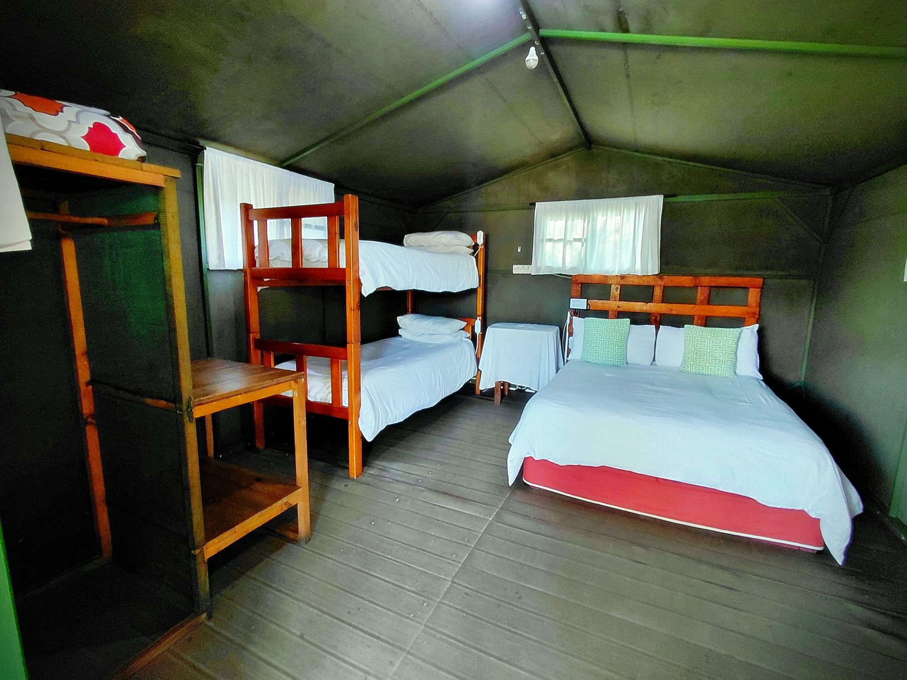 Four single beds arranged inside the tent on stilts